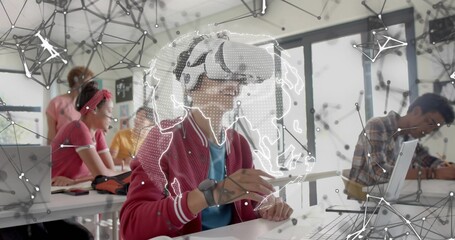 Exploring red-jacketed teenager with VR headset holding stylus in class, with AR globe and laptops