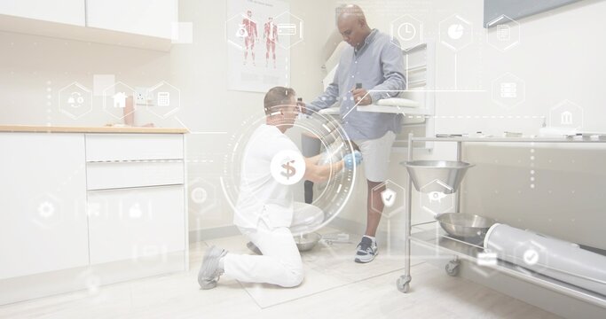 Kneeling clinician examining patient's lower leg on folded mat in clinic, white scrubs, gloves, HUD