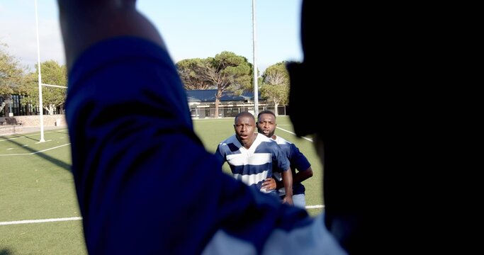 Standing two rugby players wearing blue-white striped jerseys preparing on grassy pitch with post