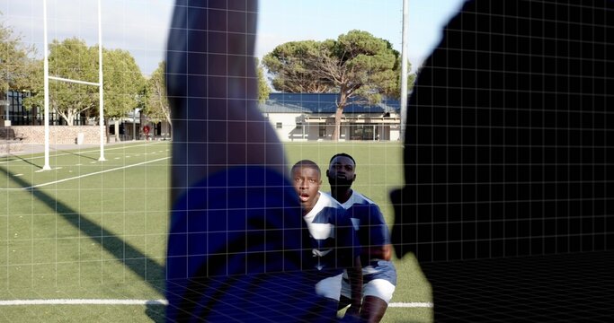 Reacting kneeling player looking at camera on rugby pitch, silhouette blocking, wearing striped kit