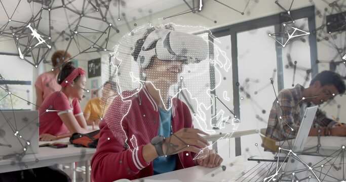 Exploring red-jacketed teenager with VR headset holding stylus in class, with AR globe and laptops