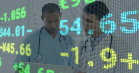 Analyzing laptop, MDs in scrubs, lab coat and tie with stethoscopes viewing finance data in clinic