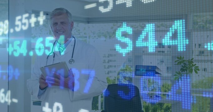 Standing mature doctor in white coat holding clipboard in clinic, with stethoscope and ticker