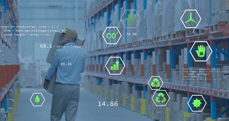 Carrying two cardboard boxes, warehouse worker in plaid shirt and cap walking racked aisle with HUD