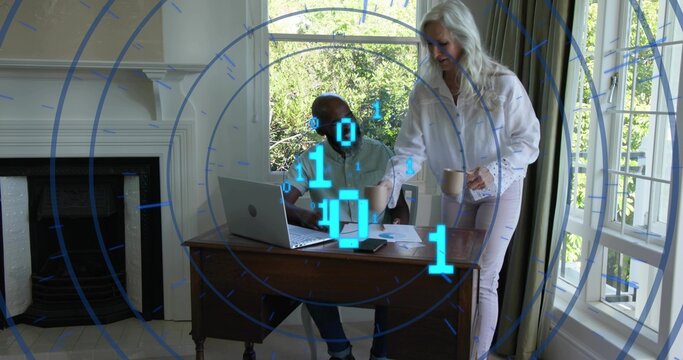 Reviewing senior woman and mature man sharing laptop and papers at home office, with blue overlay - Powered by Adobe