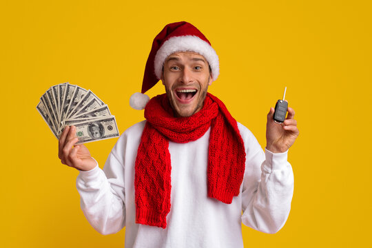 A man wearing a Santa hat and a red scarf is joyfully holding a stack of cash in one hand and car keys in the other. His bright smile conveys holiday excitement and cheer.