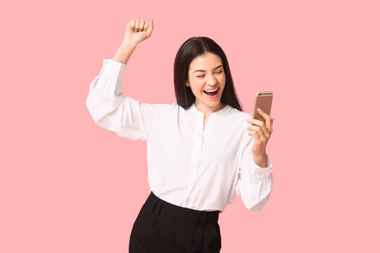 Happy businesswoman with mobile phone on pink background