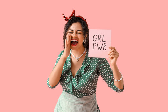Young African-American pin-up woman with GRL PWR sign shouting on pink background. Women's History Month