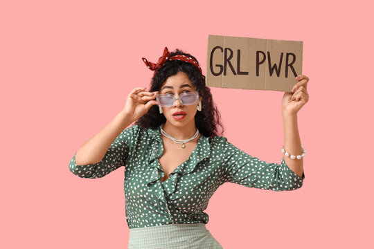 Young African-American pin-up woman with GRL PWR sign on pink background. Women's History Month
