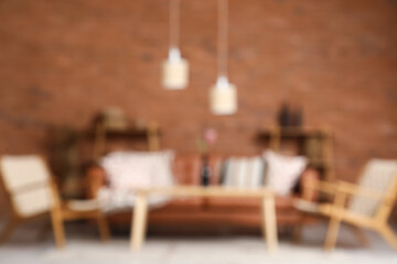 Cozy sofa, wicker armchairs and coffee table in interior of living room. Blurred view