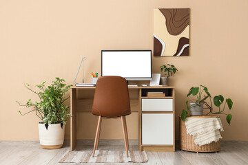 Stylish workspace with modern computer and houseplants near beige wall