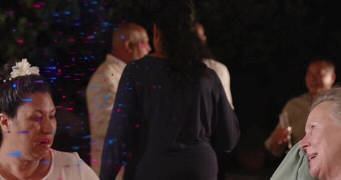 Two women chatting then walking to mingle holding drinks as speckled light floating over event