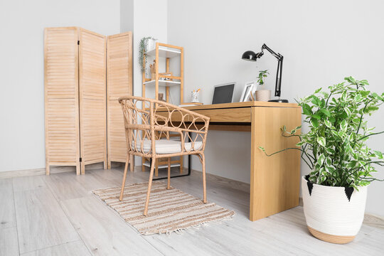 Stylish workspace with modern laptop and desk lamp near white wall