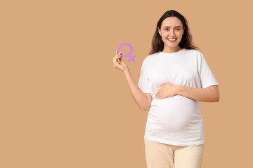 Young pregnant woman with gender symbol on beige background