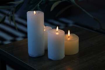 Burning candles on table in dark living room, closeup
