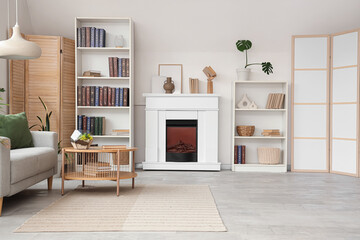 Fototapeta premium Shelving units with books, fireplace, sofa and coffee table in interior of stylish living room