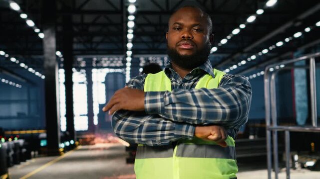 African american worker in a plant handles automation equipment, emphasizing engineering skill, production accuracy, and the protective gear required in heavy industrial operations. Camera B.