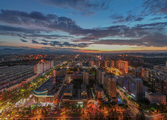 Aerial view of city neon under the sunset and fiery clouds