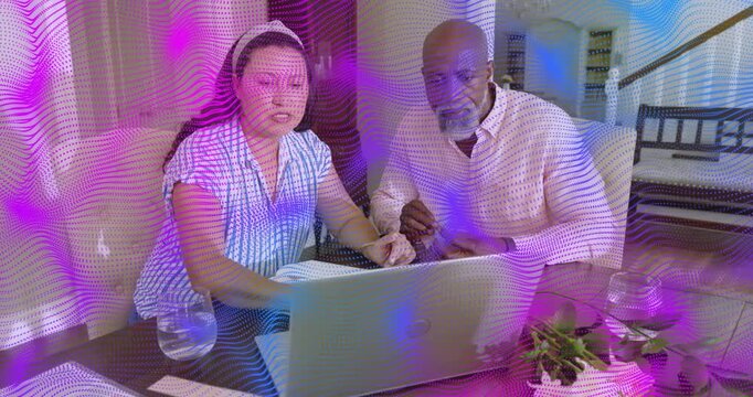 Woman pointing laptop, starting review as man holding papers, purple overlay showing finance charts