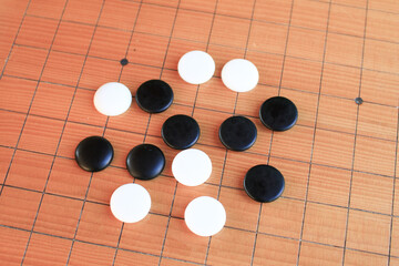 GO Japanese traditional game playing black and white stone pieces on wooden grid board. Strategy and concentrate game  