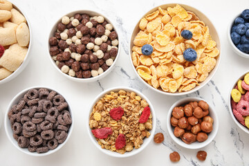 Bowls with different cereals on marble background, closeup
