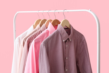 Rack with stylish collar shirts on pink background