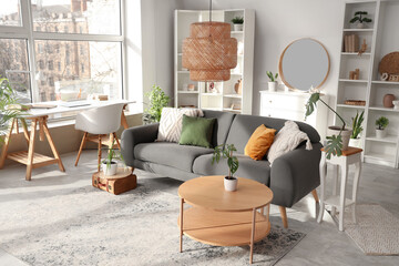 Interior of stylish living room with grey sofa, coffee table and mirror