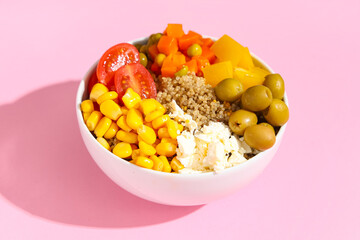 Healthy quinoa bowl with vegetables on pink background, closeup