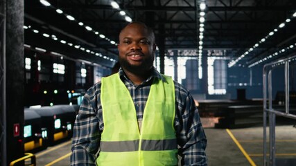 Portrait of african american technician wearing workshop equipment in a warehouse industry plant, demonstrating manpower and engineering behind manufacturing efficiency. Camera A.