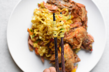 Overhead view of egg noodles noodles in wooden chopsticks, top view of Singaporean fusion noodles in chopsticks