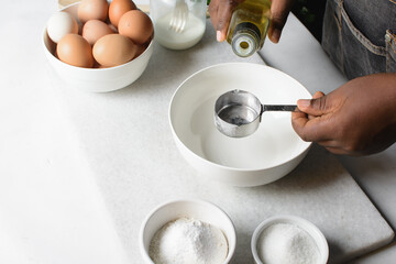 Oil being poured into a silver measuring cup