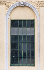 Arched window of a historic building with stucco and decorative frame in a classical architectural style