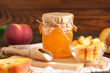 Jar of jam, fresh peaches and scoop of sugar on wooden background