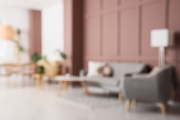 Blurred view of stylish living room with grey sofa, armchair and dining table