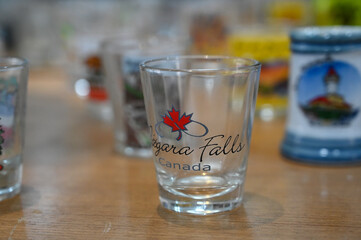 collection of shot glasses on wooden shelf, souvenir mugs and small decorative cups display, close up of glass shot collection inside,miniature souvenir cups
 , travel theme and various designs