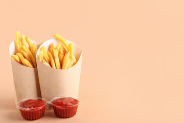 Paper boxes with tasty french fries and ketchup on orange background