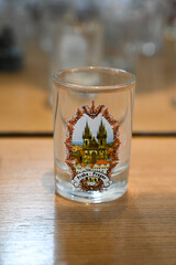 collection of shot glasses on wooden shelf, souvenir mugs and small decorative cups display, close up of glass shot collection inside,miniature souvenir cups
 , travel theme and various designs