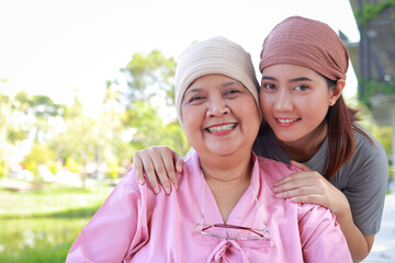 Portrait of Asian mother and daughter. Elderly mother with cancer wearing headscarf after chemo. Daughter wearing head scarf to keep her mother company. Family concept. Elderly care.