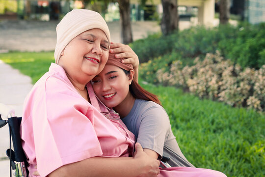 Daughter hugs her elderly mother with cancer wearing a headscarf after chemo. Daughter wears a headscarf to keep her mother company. Family concept. Elderly care.