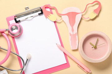 Blank clipboard with paper uterus, alarm clock and stethoscope on beige background. Gynecology concept