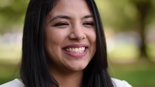 Young woman smiling outdoors, happiness expressed with blurred foliage background, great for ads