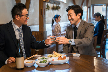 A businessman having fun drinking with his subordinates at an izakaya/bar

