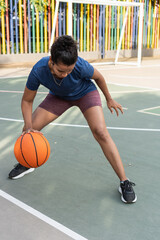 Fototapeta premium Woman dribbling basketball on court for exercise