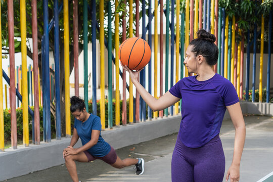 Women stretching and playing basketball outdoors together