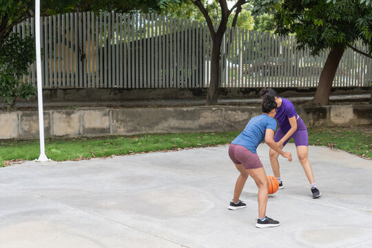 Women playing one on one basketball game outdoors - Powered by Adobe