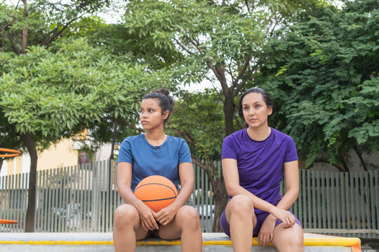 Women basketball players sitting pensive on court