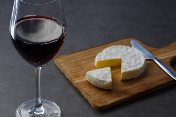 Glass of Wine with camembert cheese on the wooden cutting board on the table
