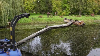 Cleanup of a pond in a public park removes algae and debris with a specialized machine in late autumn