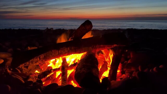 A campfire on the Black Sea coast in Tuapse. A campfire built on pebbles. A picnic at night by the sparkling logs of a campfire. A sunset on the slope of the Caucasus Mountains. 4К