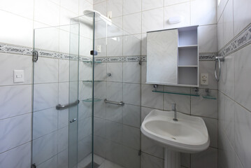 clean functional bathroom interior, white tile with blue accent border, pedestal sink and glass shower, practical small washroom design, bright hygienic toilet and basin, residential apartment rental